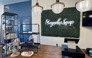 Interior of Magnolia Soap boutique with neon signage on a green hedge wall and pendant lighting, Brookfield Wisconsin